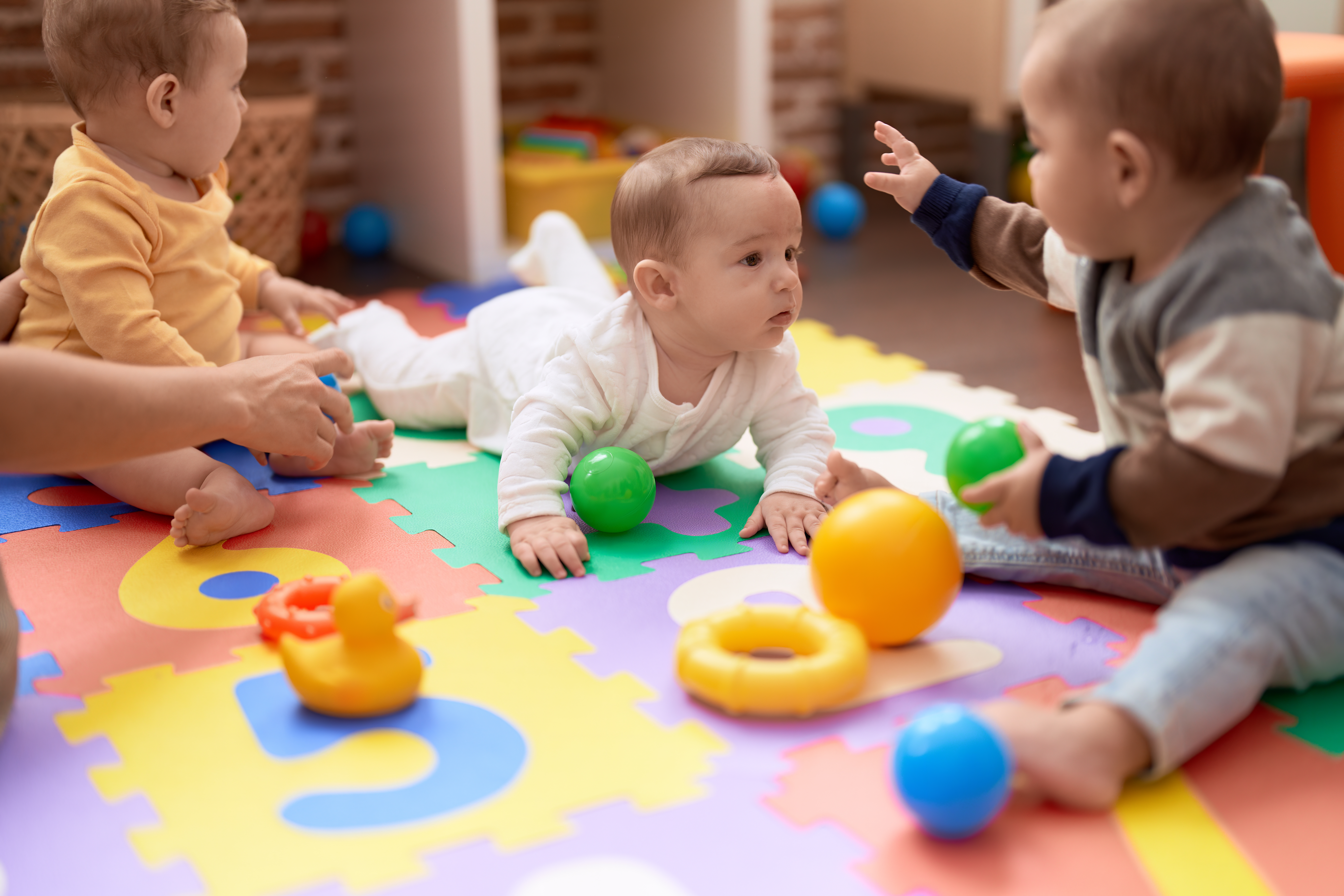Group of toddlers playing with toys crawling on floor at kindergarten