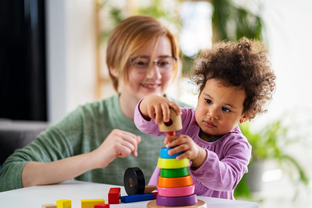 Educator looking at a child playing with stacking rings