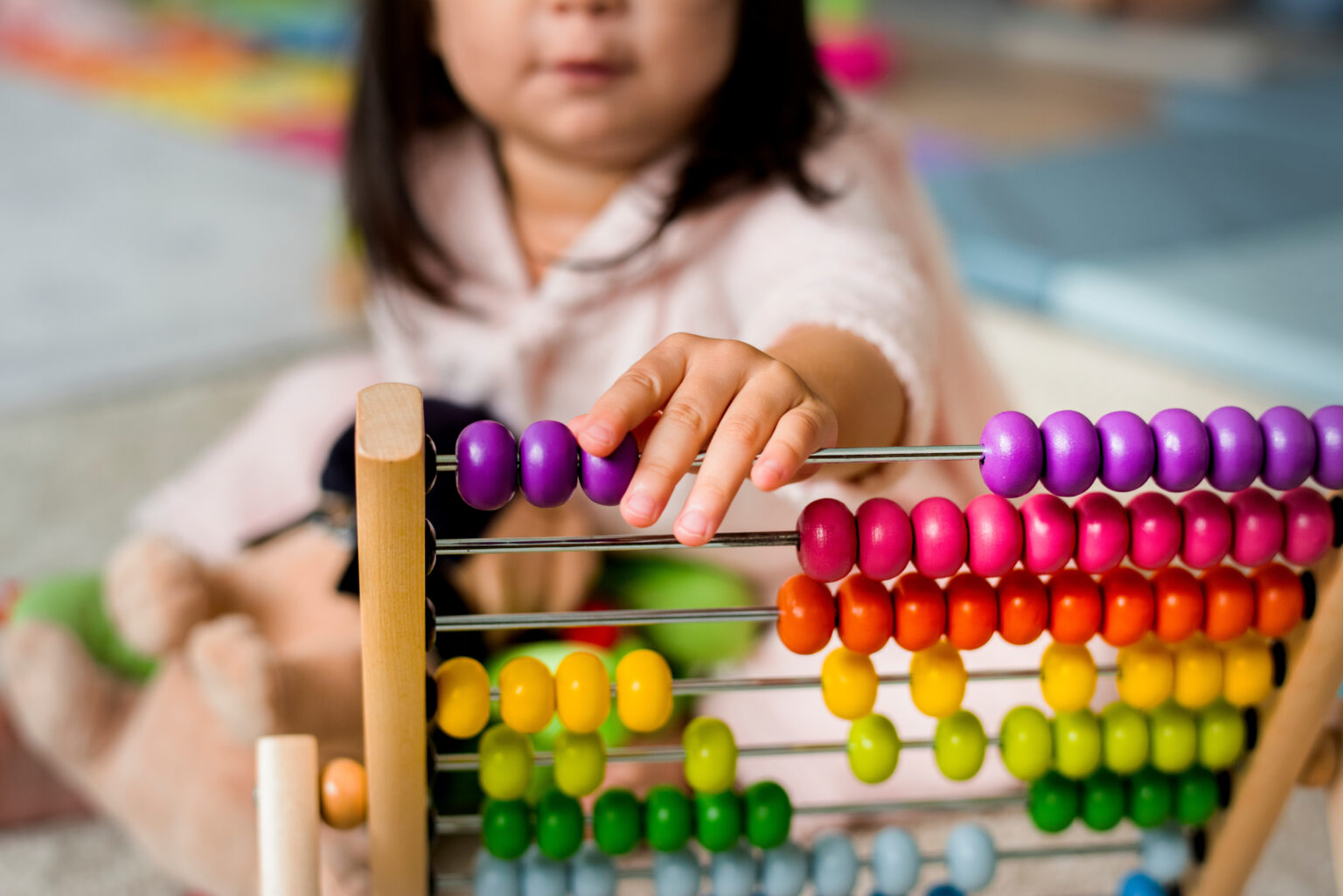 Little girl playing with a colourful wooden abacus
