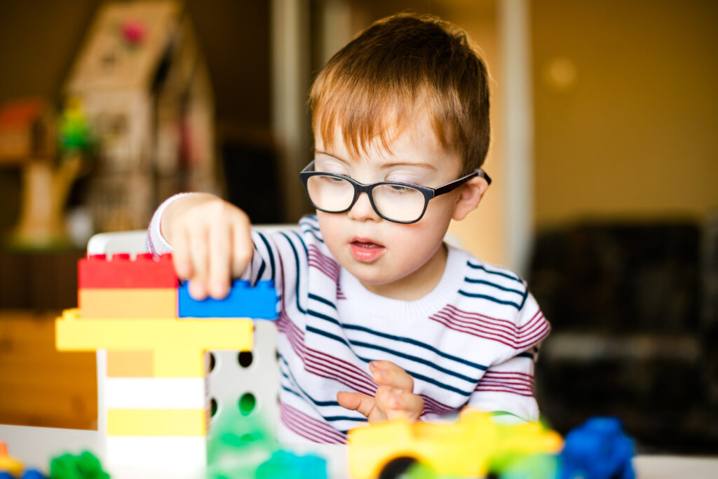 Little boy wearing glasses stacking building blocks