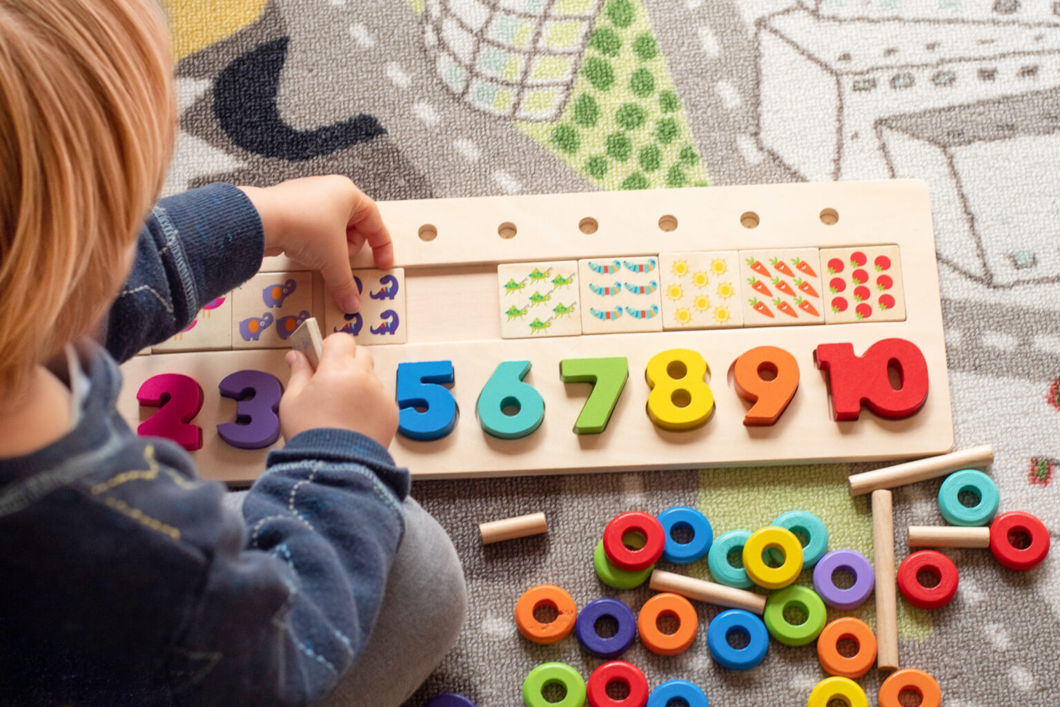 little boy playing with a wooden number sorting toy