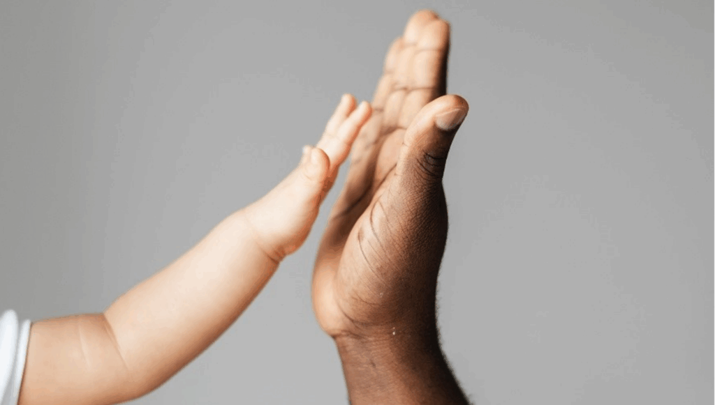 A small child's hand reaching out to touch a larger adult's hand