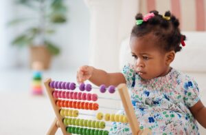 Little girl sat on the floor playing with a colourful abacus