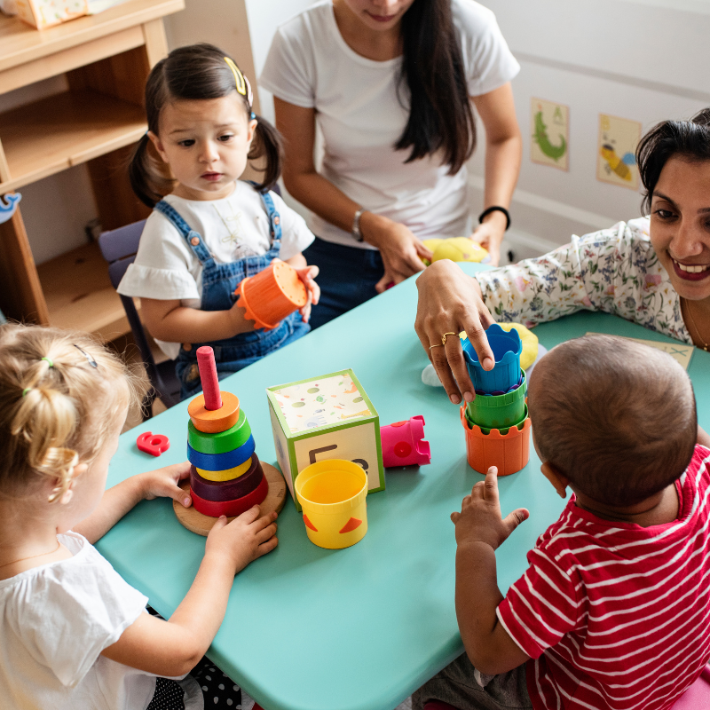 Children sat around a table playing with two adults