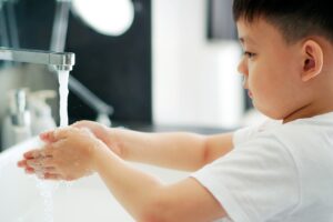 Young boy washing his hands under a tap at the sink
