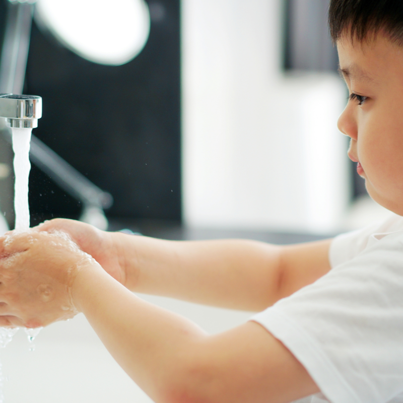 Young boy washing his hands under a tap at the sink