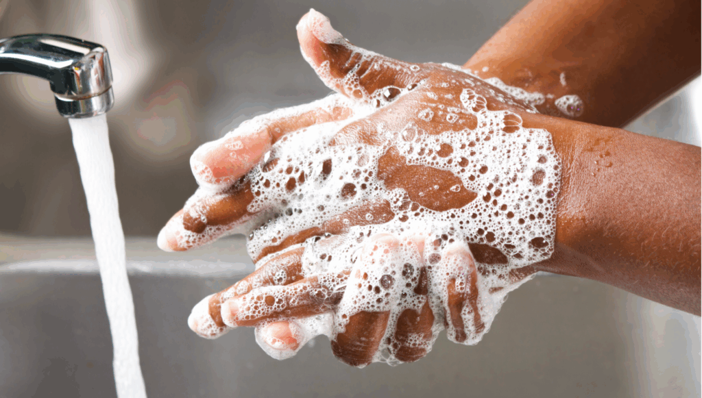 Close up of a child's hands being washed with soapy water