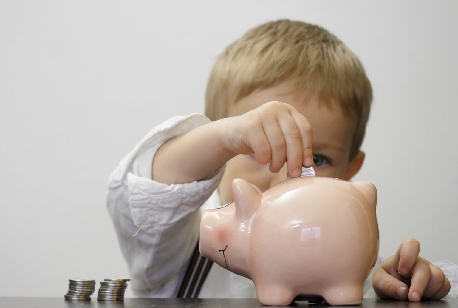 Little boy placing coins into a piggy bank
