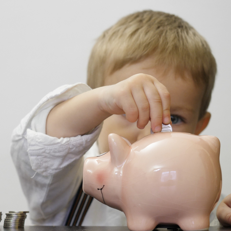 Little boy placing coins into a piggy bank
