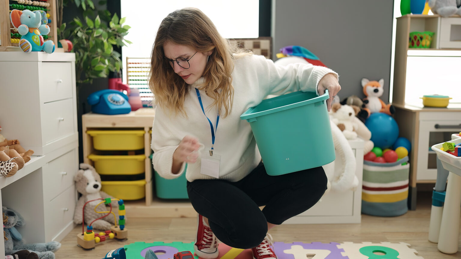 Preschool teacher picking up toys at kindergarten