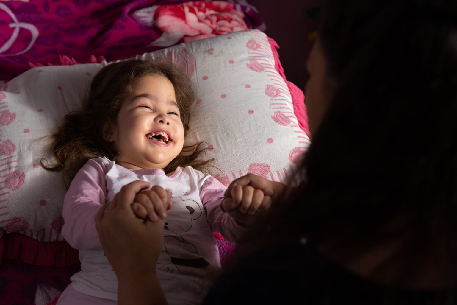 Little girl with a disability lying on her bed looking up and laughing