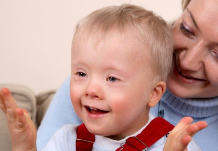 Little boy with a disability sat smiling on his mother's lap