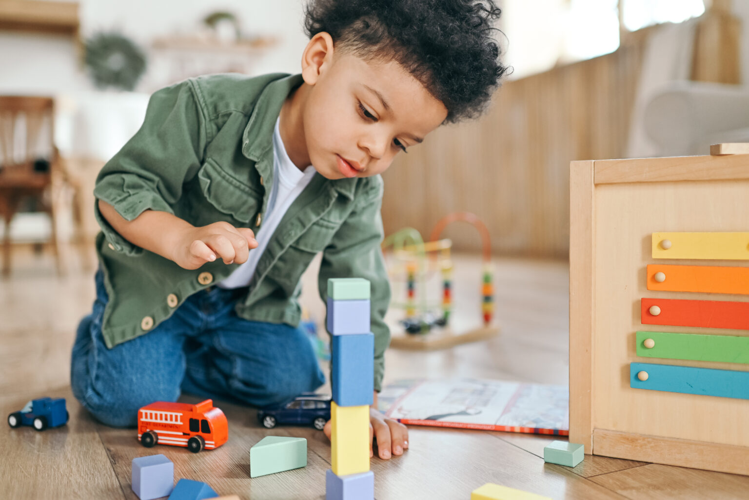 Little boy carefully building a stack of colourful building blocks