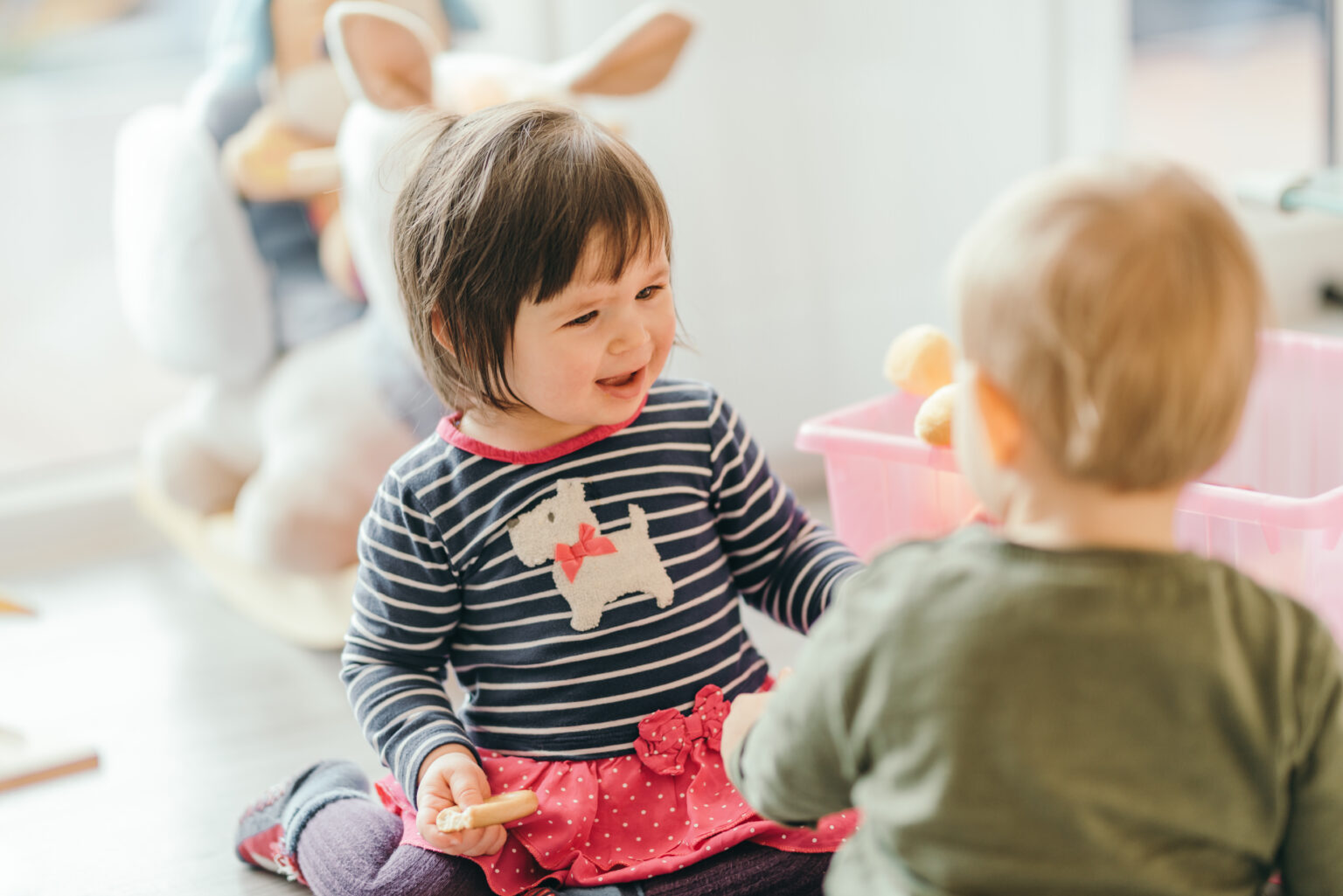 Smiling little girl and boy playing with toys on the floor