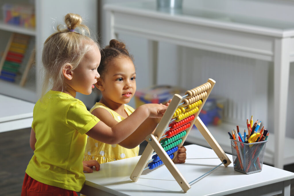 Children sit together at the table and count on the abacus and smiles