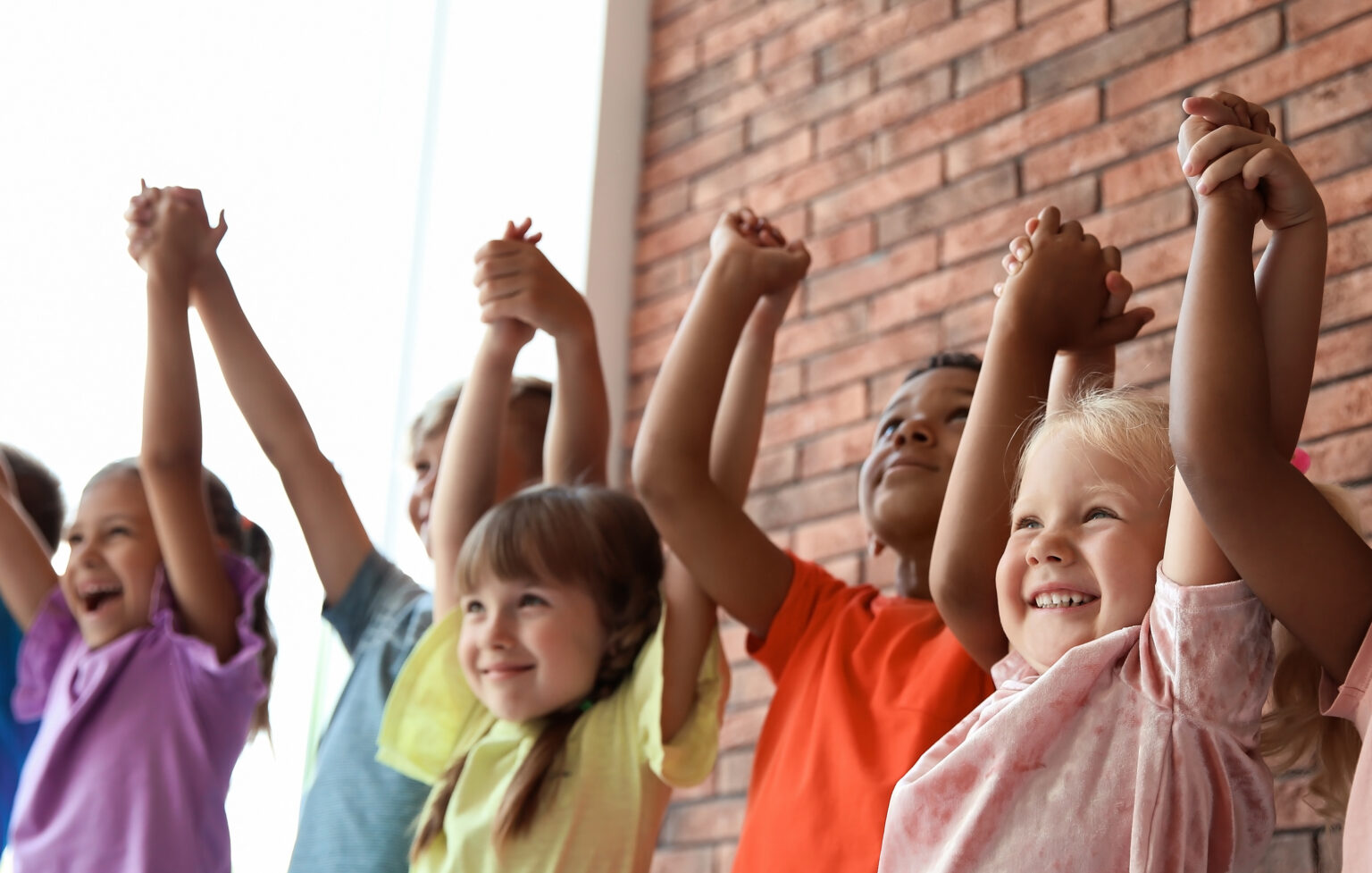 Little children holding hands together indoors.