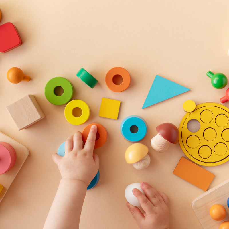 Child's hand reaching into a selection of colouring wooden blocks and shapes
