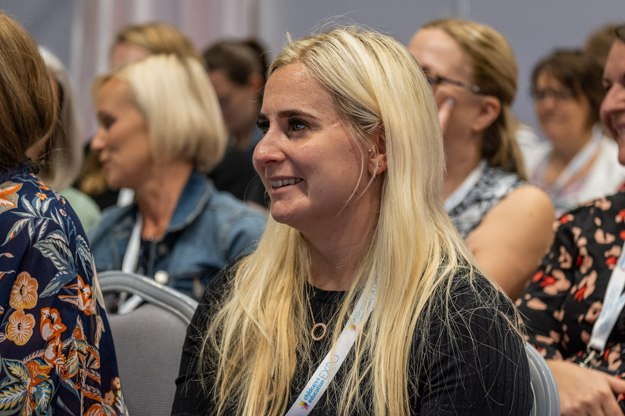 A blonde woman sits in the audience at the Childcare and Education Expo