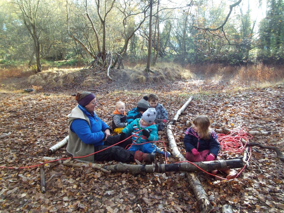 Julie and the children building in the forest with branches and rope
