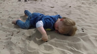 Boy, aged 2, explores dry sand