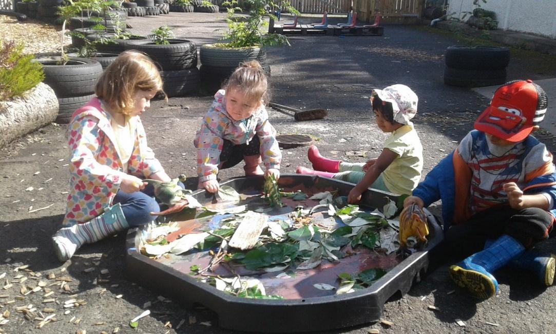 Children aged 2, 3 and 4 engaged in play with dinosaurs