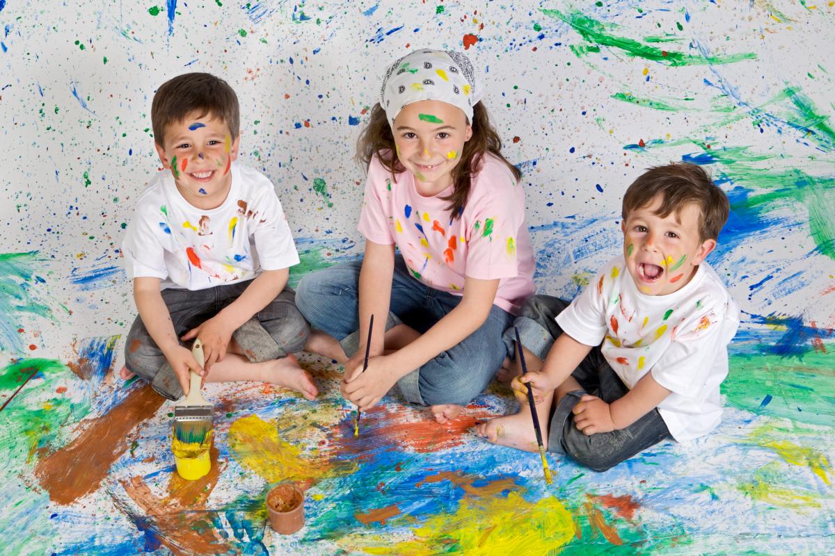 three children sit in messy play paint