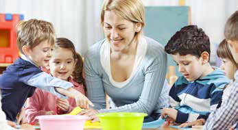 a woman watches as children show her different coloured bowls