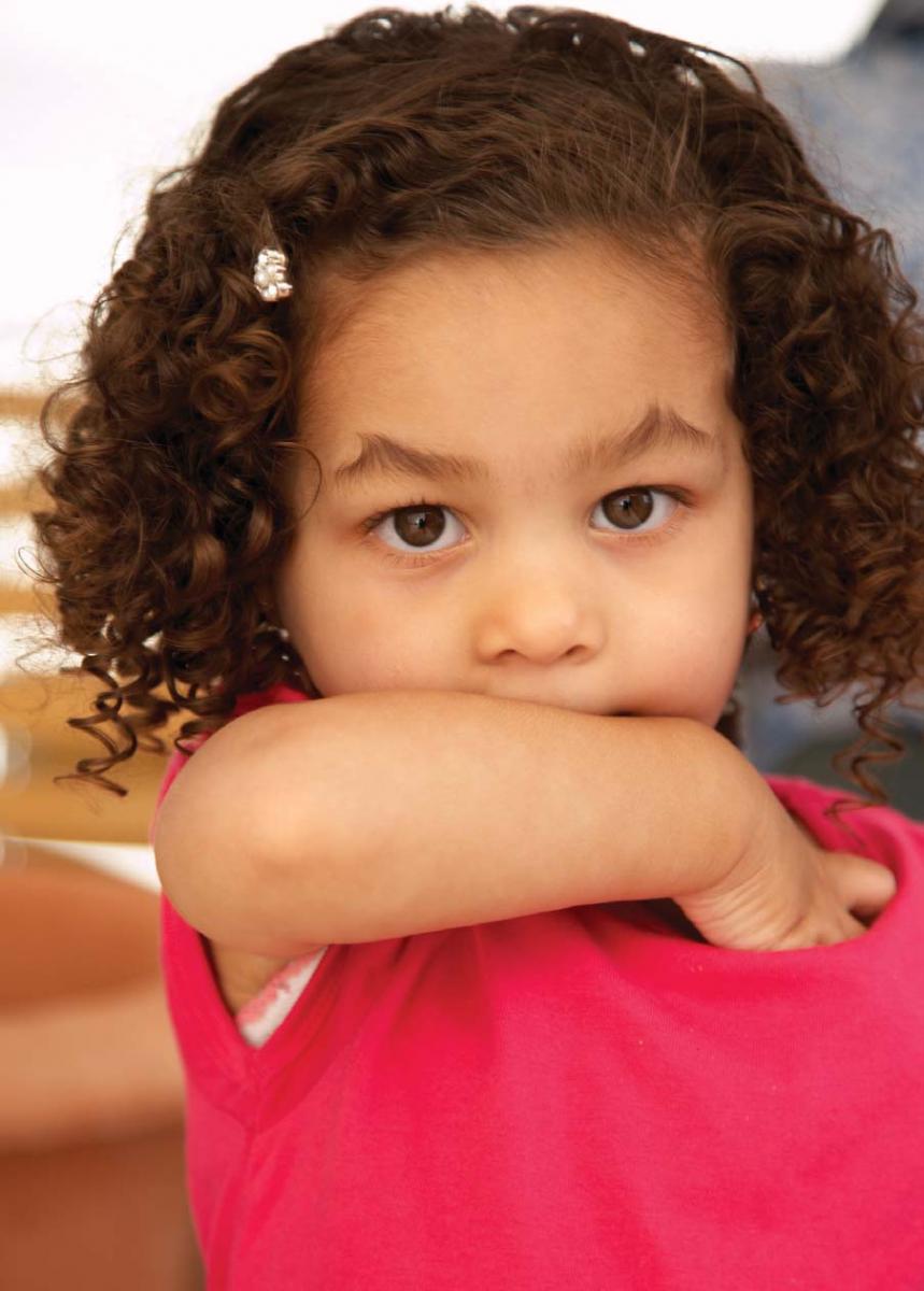 young girl covers mouth with arm