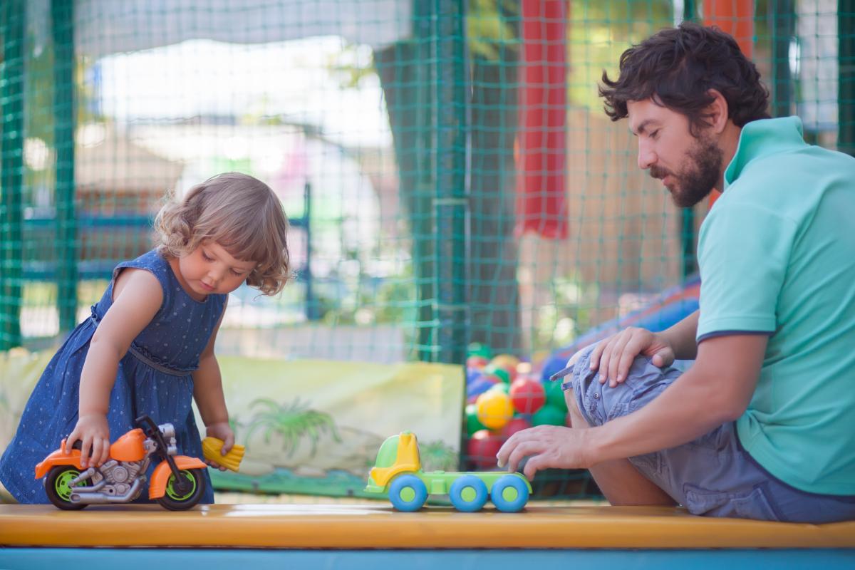 Young male practitioner and girl play with trucks