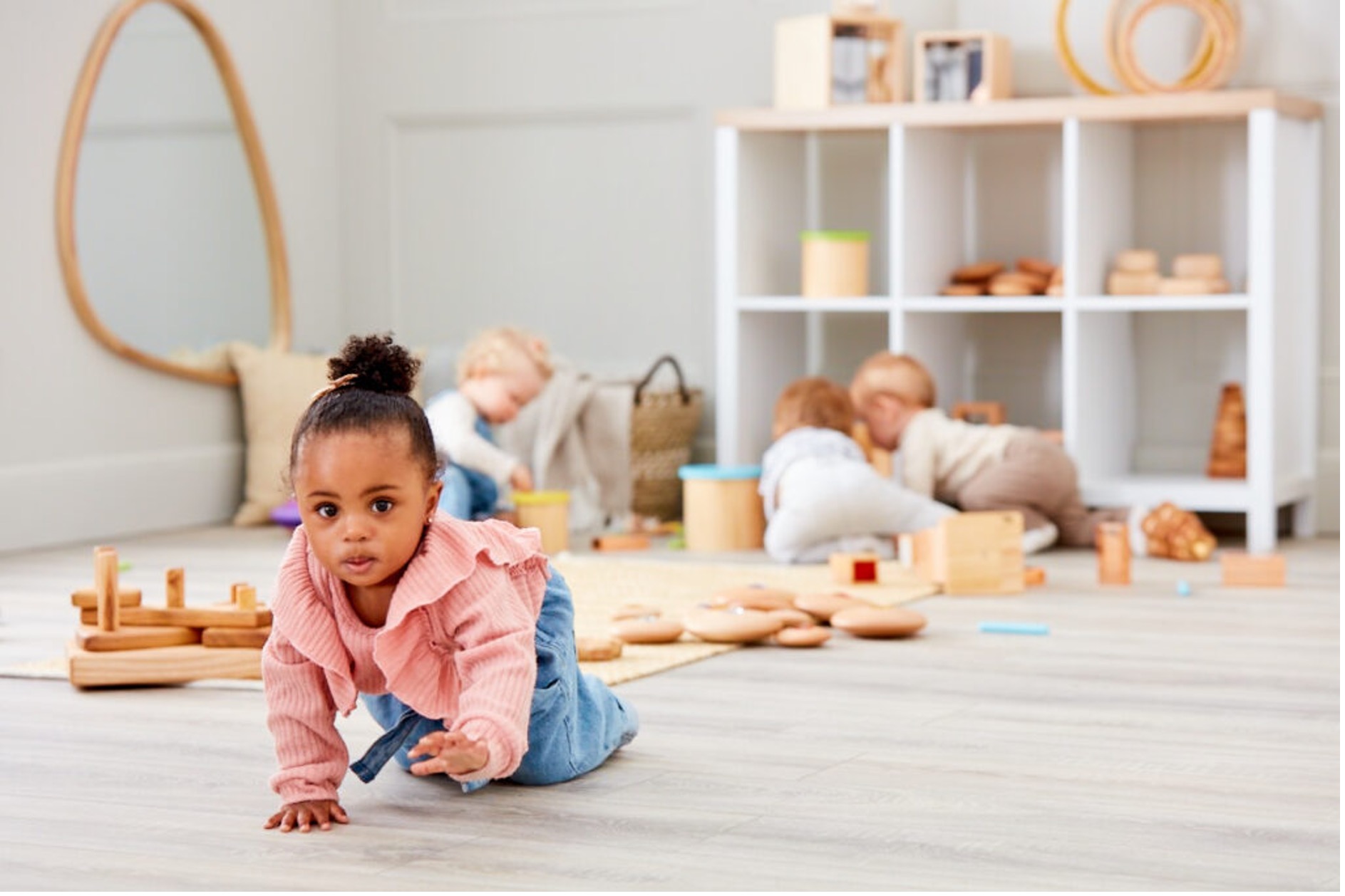 toddler crawling towards camera, with toddlers in background playing and crawling