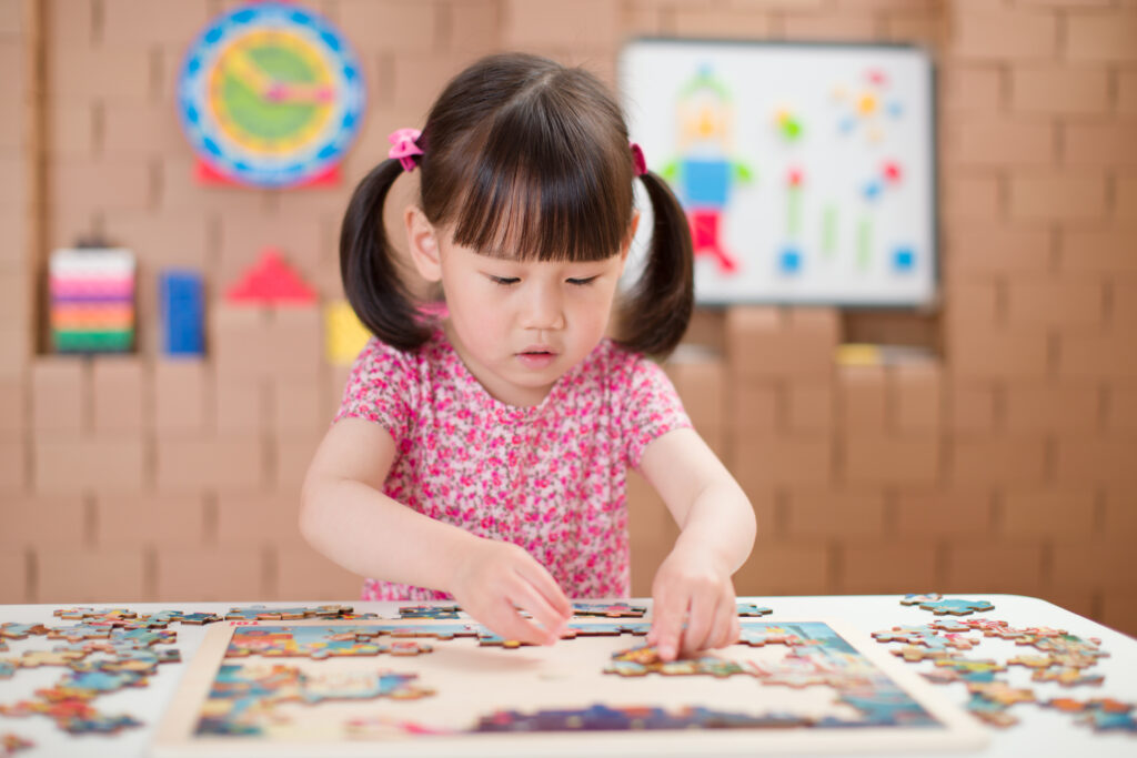 toddler girl playing wooden puzzle at home