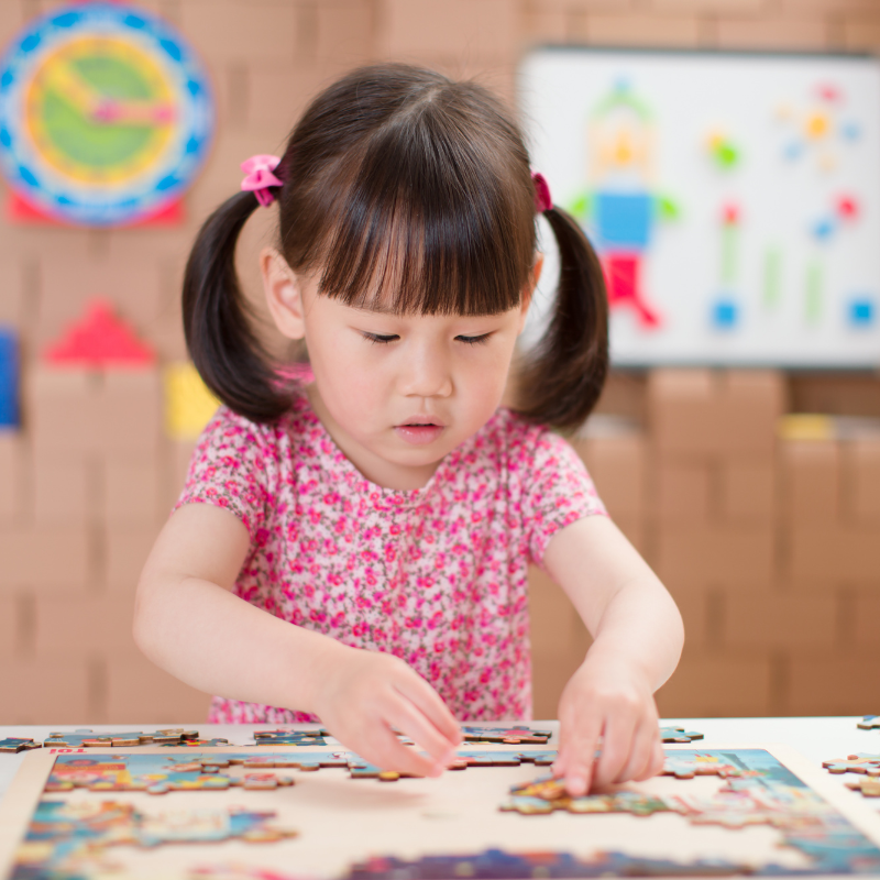 toddler girl playing wooden puzzle at home