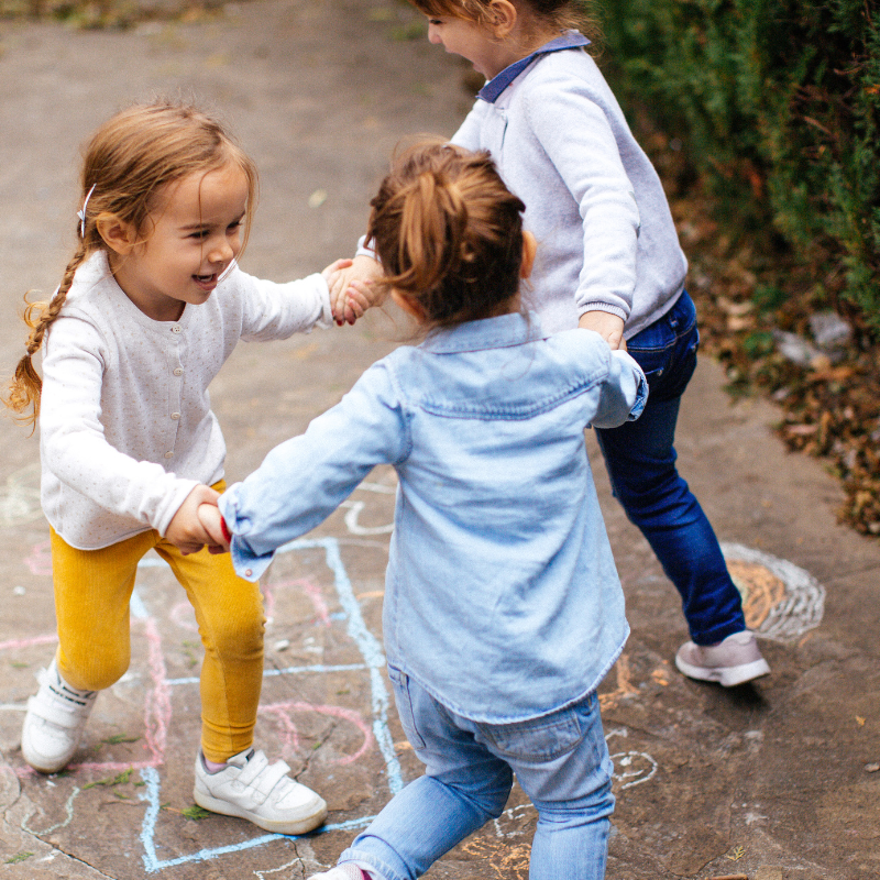 Little girls holding hands skipping in a circle