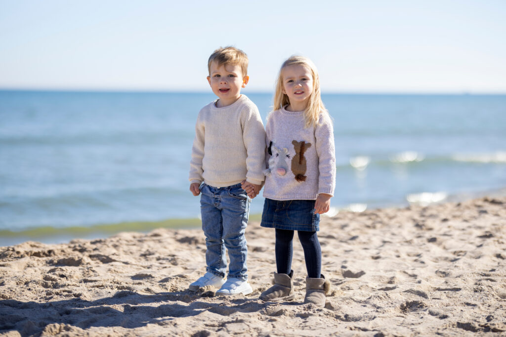 Two toddlers holding hands on the beach