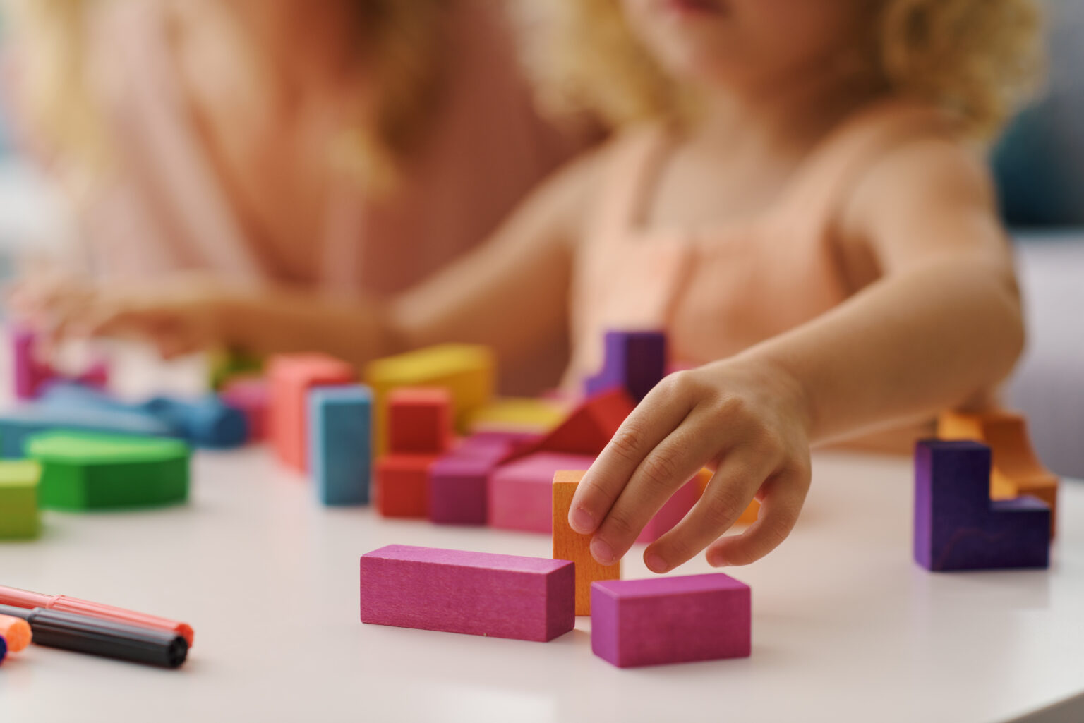 Little girl's hand reaching for colourful wooden blocks