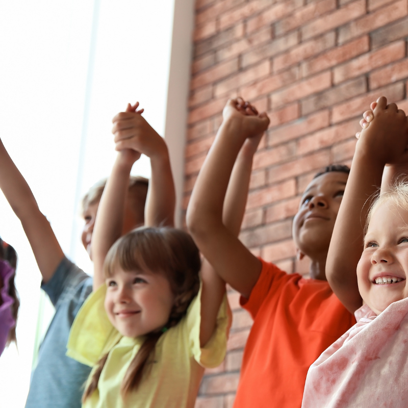 Little children holding hands together indoors.