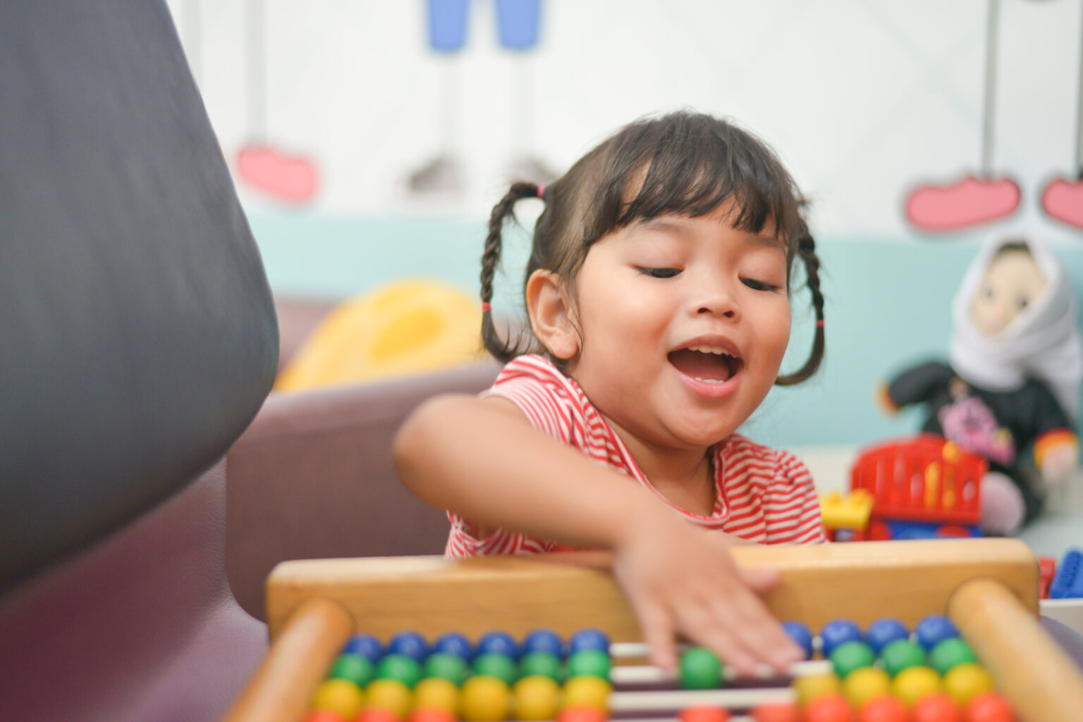 Little girl with pigtails moving beads on a horizontal abacus