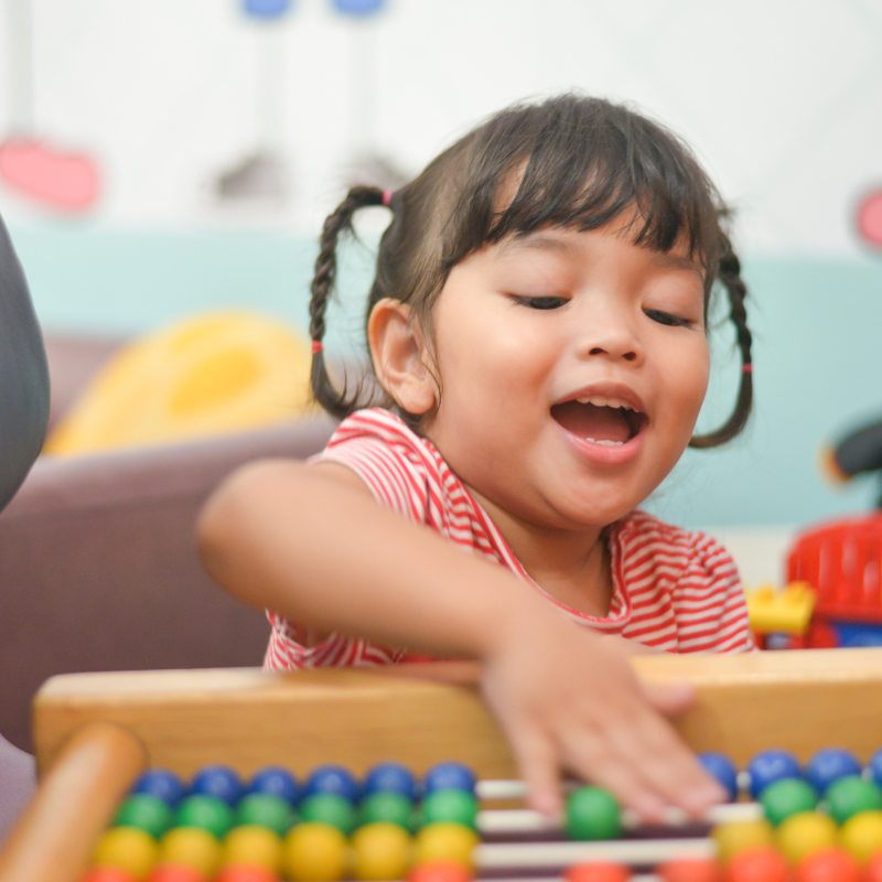 Little girl with pigtails moving beads on a horizontal abacus
