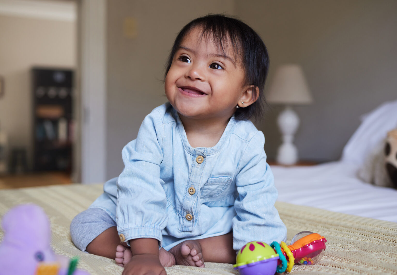Smiling little girl on a bed with toys