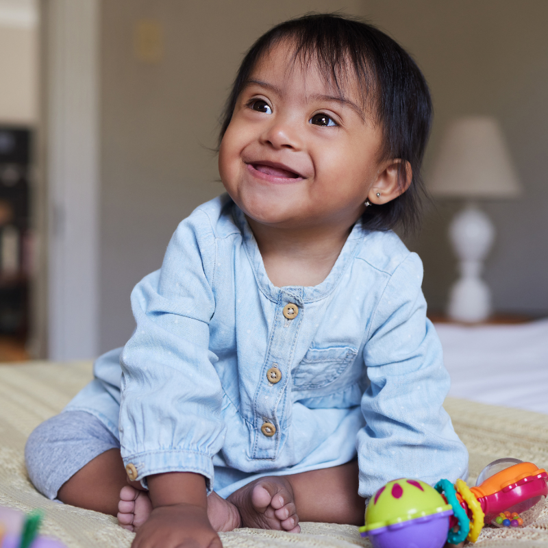 Smiling little girl on a bed with toys