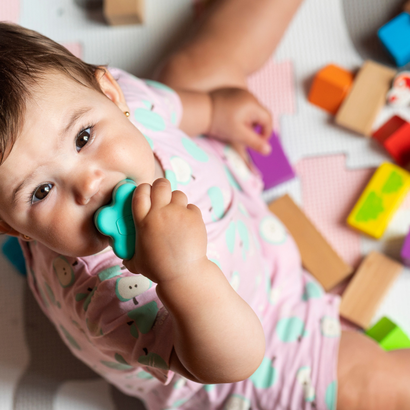 Toddler at on the floor surrounded by colourful toys
