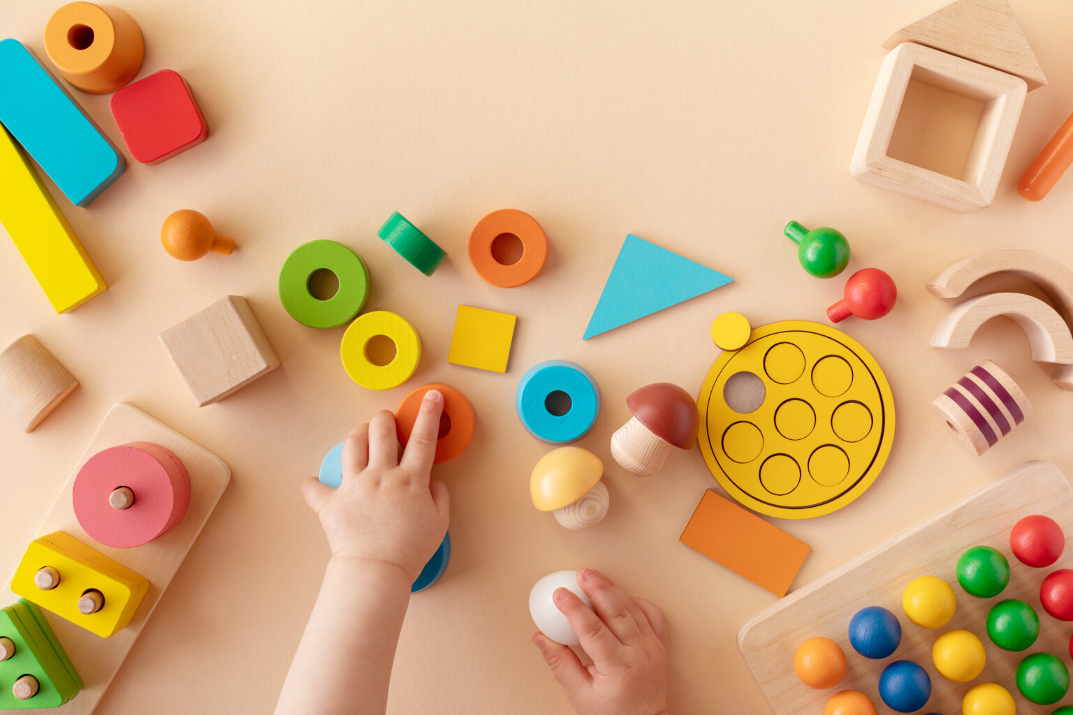 Child's hand reaching into a selection of colouring wooden blocks and shapes
