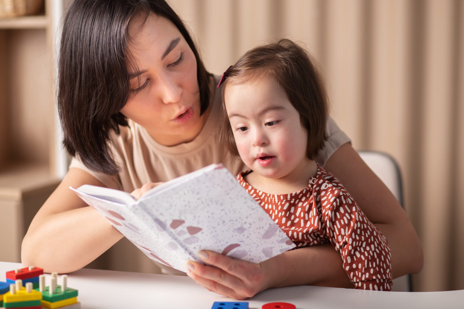 Woman reading to a little girl who is sat on her lap
