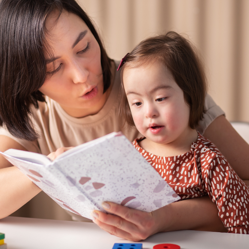 Woman reading to a little girl who is sat on her lap