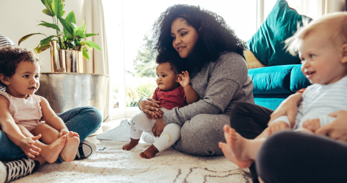 Group of mothers sat on the floor with their babies in their laps