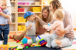 Two mums sit and play with their children and a selection of brightly-coloured toys