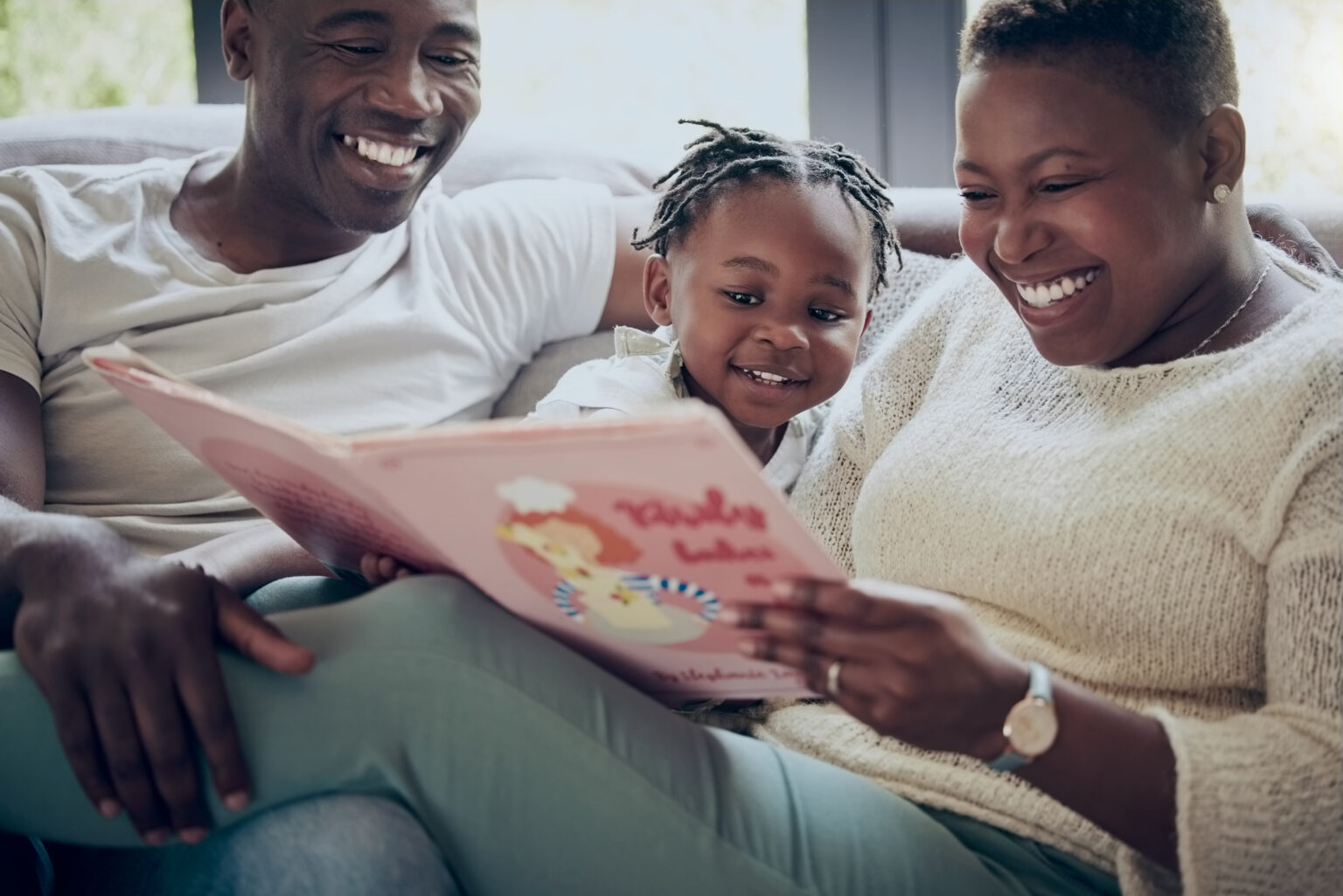 Family of mum, dad an child reading together on sofa