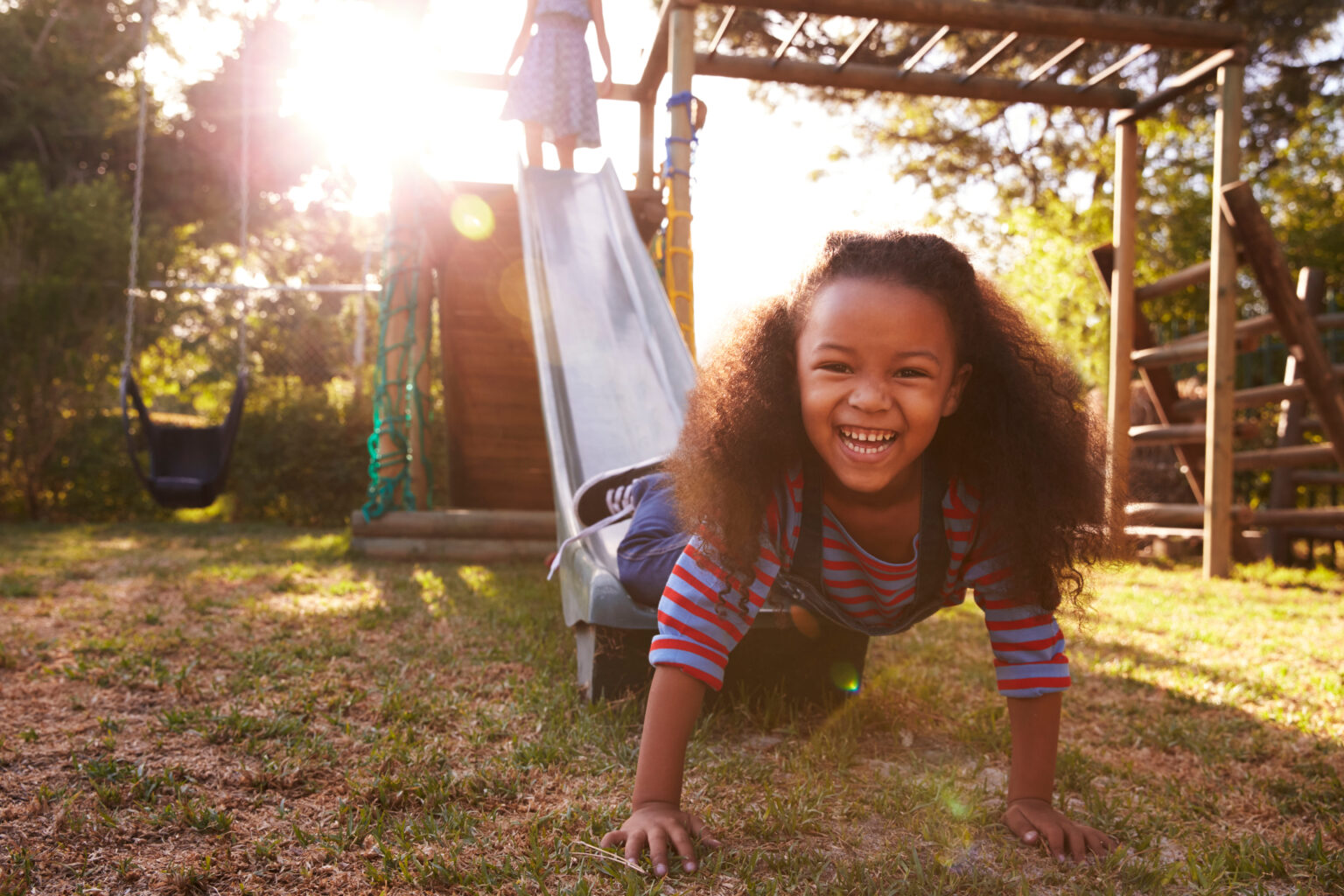 Smiling child climbs off the bottom of an outdoor slide